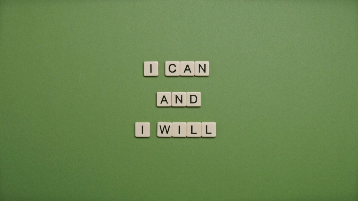 Scrabble tiles arranged with the phrase 'I CAN AND I WILL' on a green background
