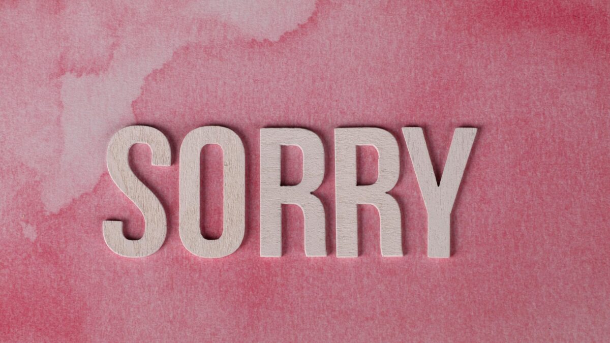 The word 'SORRY' written in large, white letters on a pink watercolor background.