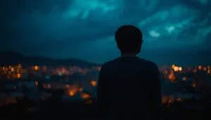 Person standing alone overlooking a city at night symbolizing emotional growth, self-reflection, and solitude in adulthood